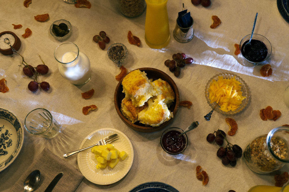 A San Gabriel Homestead breakfast, featuring golden croissants, sliced bread, jam, sliced ham and cheese.